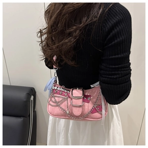 Detail of pink Y2K shoulder bag with silver chains, star studs and a checkered bow charm
