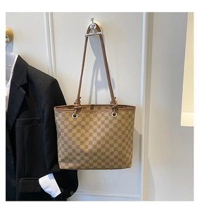 Detail of vintage checkered tote bag hanging on wall beside a black blazer
