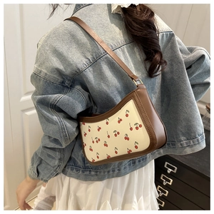 Detail of trendy cherry print shoulder bag worn by model showing size and fit on body