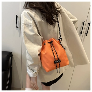 Détail du sac seau en nylon orange avec bandoulière tissée et étiquette Creative Spirit