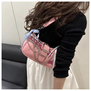 Detail of pink shoulder bag with silver star rivets, metal chain and blue plaid ribbon