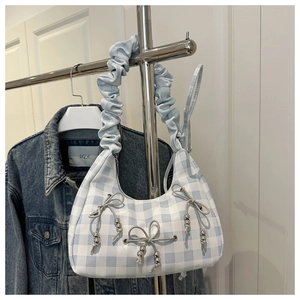 Detail of light blue gingham handbag featuring scrunchie handle and beaded bows
