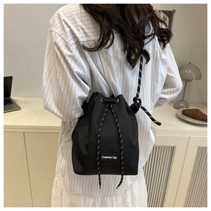 Détail du sac seau noir à cordon avec étiquette Creative Cat et bandoulière en corde