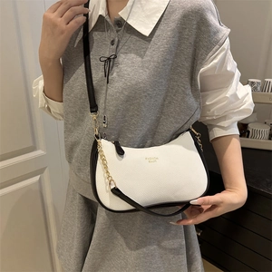 Minimalist beige pebble leather tote bag with black trim and chain strap shown on model