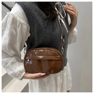 Detail view of brown patent leather crossbody bag with metallic gold zipper finish