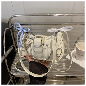 Detail of cream Y2K shoulder bag with star rivets, metal buckle and ribbon bow