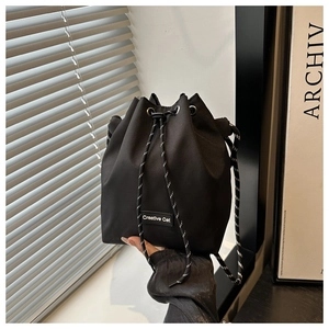 Détail du sac seau en nylon noir avec écusson Creative Cat et cordon de serrage tissé