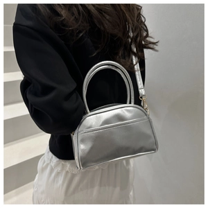 Detail of silver half-moon handbag with gold hardware and adjustable strap on model