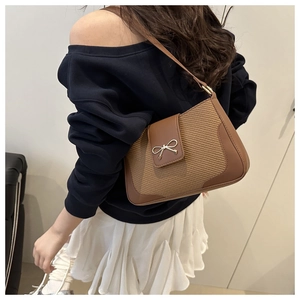 Détail d'un sac bandoulière marron tissé avec boucle nœud métallique et lanière cuir