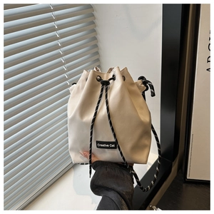 Détail d'un sac seau avec cordon, écusson Creative Cat et bandoulière tressée