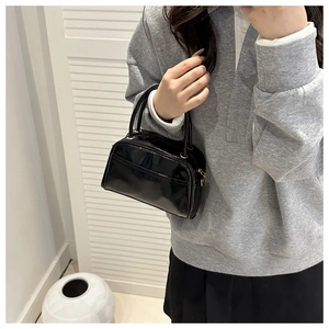Close-up of black patent leather mini Boston bag with glossy finish and metal zipper