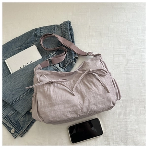 Detail of light purple nylon shoulder bag with pleated texture and decorative bow accent