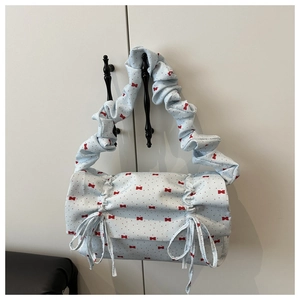 Close-up of light blue shoulder bag with red bow pattern and ruffled handle detail
