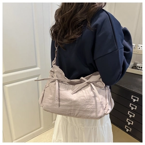 Detail of light purple nylon shoulder bag featuring decorative bows and side pleats