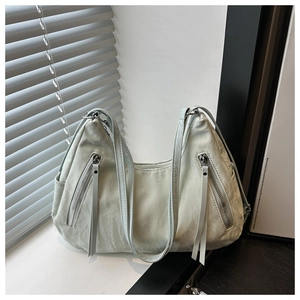 Detail view of light green tote bag with wrinkled faux leather and fringe zippers