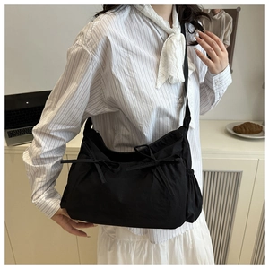 Detailed view of black tote bag featuring side drawstring pockets and sweet ribbon bows