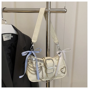 Detail of off-white chain bag featuring heart cutouts and blue plaid ribbon accents