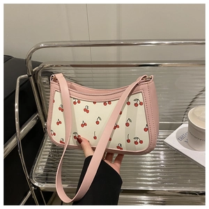 Detail of pink and beige shoulder bag with cherry print in a cafe setting