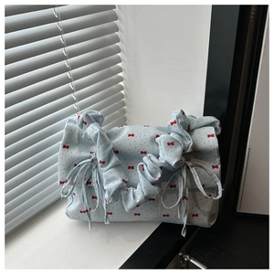 Detail of light blue floral canvas bag featuring red bow prints and a scrunchie strap