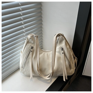 Detail of off-white faux leather tote with silver zipper accents and textured pleats