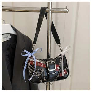 Detail of punk style underarm bag with silver chains, rivets and bow charms on a hanger