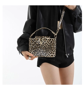 Detailed view of leopard print crossbody bag with metallic V buckle and leather texture