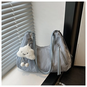 Detail of light blue textured shoulder bag with functional zippers and cloud charm