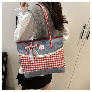 Detail of red checkered tote bag with white lace trim, cherry patch and bow accent