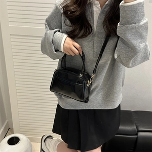 Chic black patent leather mini Boston bag worn as a crossbody with a grey sweatshirt