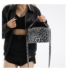 Detail shot of the golden V-shaped metal buckle on the leopard print crossbody bag
