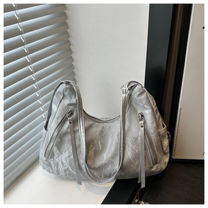 Detail of silver pleated tote bag with metallic texture and diagonal zipper pockets