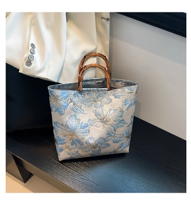 Gros plan d'un sac cabas en jacquard floral avec anses en bambou naturel de style rétro