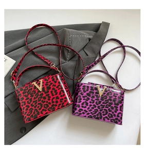 Close-up of red and purple leopard print handbags featuring elegant gold V-logo buckles