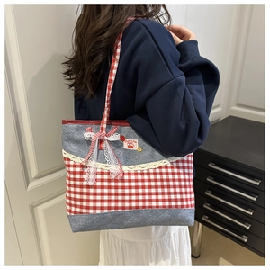 Close-up of red plaid canvas tote bag with denim patchwork, lace trim and bow detail