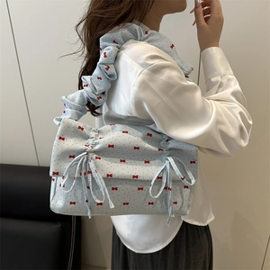 Hellblaue Achseltasche mit roten Schleifenmustern und Faltenriemen am Modell