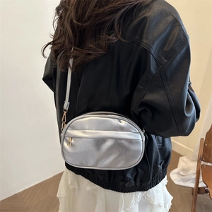 Vintage silver PU leather crossbody bag with oval design and adjustable strap on a model