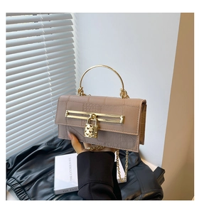 Detail der beigen Handtasche in Kroko-Optik mit Herzschloss und Metallgriff