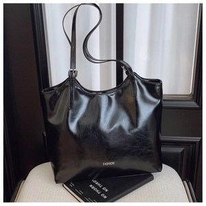 Detail der schwarzen glänzenden Kunstleder-Tasche mit weißem Fashion-Text und Metallschnalle