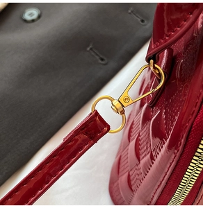 Macro shot of glossy wine red patent leather shoulder bag with gold hardware details