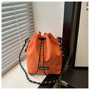 Détail du sac seau orange vif avec bandoulière tressée et logo Creative Cat