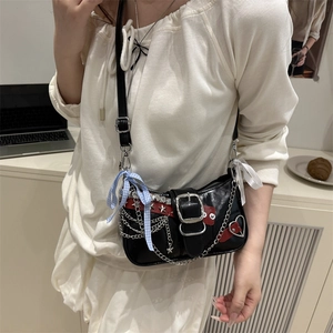 Y2K black patent leather shoulder bag with silver chains and star charms on a model