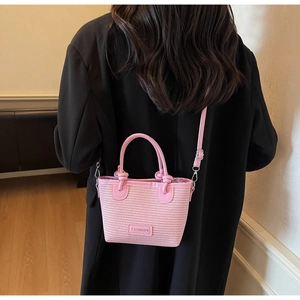 Detailed texture of pink woven bucket bag with fashion plaque and crossbody strap