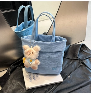 Gros plan du sac fourre-tout bleu clair texturé avec charme ours et logo de marque