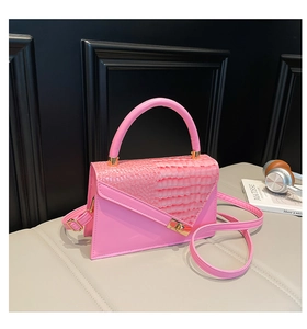 Makroaufnahme einer leuchtend rosa Handtasche mit Krokodilprägung und goldenem Metallschloss