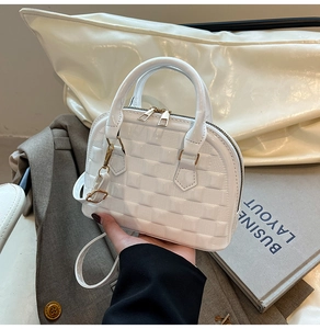 Detail of white mini shell bag featuring glossy patent leather and square embossed texture