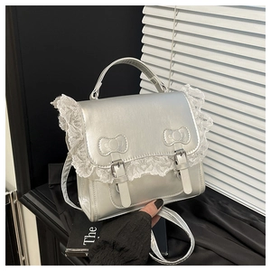 Vue détaillée du sac en cuir argenté avec bordure en dentelle et nœud embossé