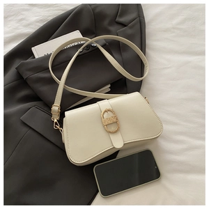 Creamy white rectangular crossbody bag with golden textured buckle and smartphone for scale