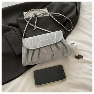 Detail of grey marbled pleated crossbody bag with chain strap and fluffy doll pendant