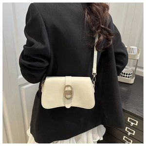Detailed view of cream PU crossbody bag with oval gold buckle worn by model in suit