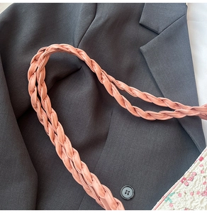 Détail de la bandoulière tressée rose et du tissu plissé floral sur un sac cabas
